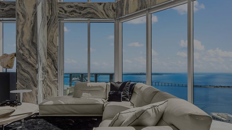 Brickell penthouse — double-height living room facing Biscayne Bay (hero, darkened for legibility) — Cardiff Photography (bp-2026 G05D)