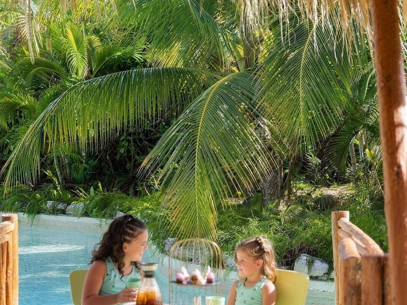 Niños en una mesa junto a la piscina en Eden Roc Cap Cana