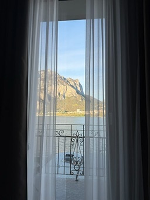 A hotel window opening onto the lake and the mountains